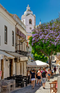 Lagos-Straßenszene in der alten Stadt mit der Kirche von Santo António und Jacaranda-Baum in der Blume Lagos-Straßenszene in der alten Stadt mit der Kirche von Santo António und Jacaranda-Baum in der Blume